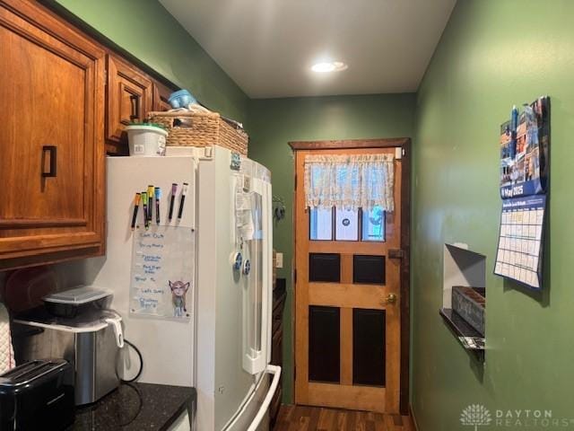 224 S Wolf Creek St, Brookville, OH 45309 - kitchen with brown cabinets, dark wood-style floors, freestanding refrigerator, and dark stone countertops