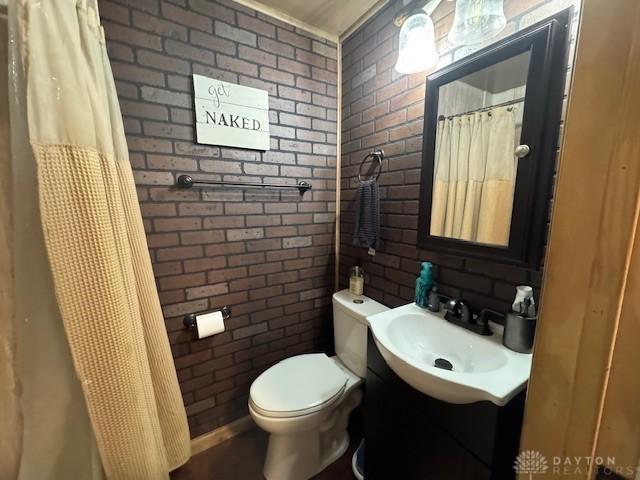 224 S Wolf Creek St, Brookville, OH 45309 - bathroom with brick wall, toilet, vanity, and a shower with shower curtain