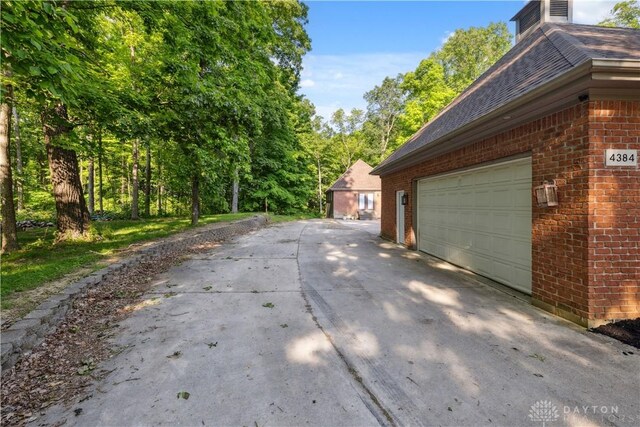 4384 New Market Banta Rd, Lewisburg, OH 45338 - view of property exterior with brick siding, a garage, roof with shingles, and driveway
