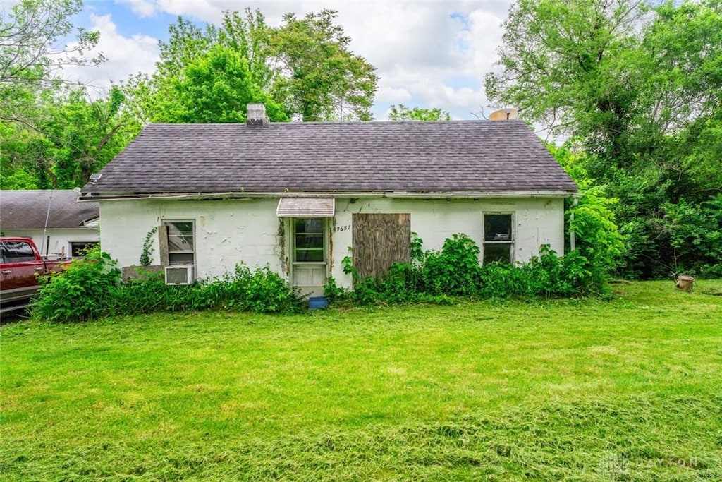 7657 Sharts Rd, Springboro, OH 45066 - view of front of house featuring roof with shingles, a front yard, a chimney, and cooling unit