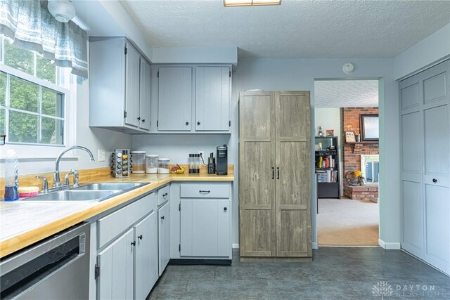 2547 Ryan Ct, Beavercreek, OH 45434 - kitchen with stainless steel dishwasher, a sink, a textured ceiling, and light countertops