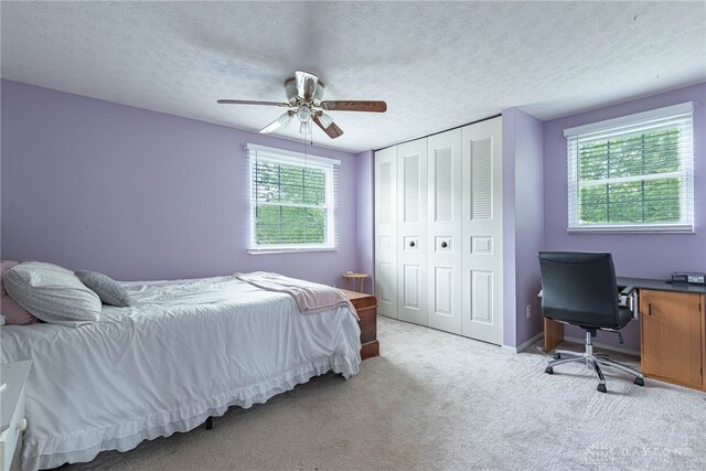 2547 Ryan Ct, Beavercreek, OH 45434 - bedroom featuring multiple windows, light carpet, ceiling fan, a closet, and a textured ceiling