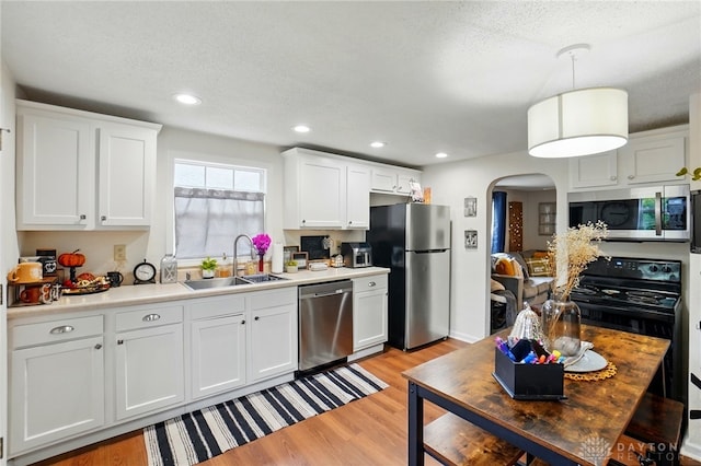 2755 S Blvd, Dayton, OH 45419 - kitchen featuring appliances with stainless steel finishes, arched walkways, light wood-type flooring, white cabinetry, and a textured ceiling