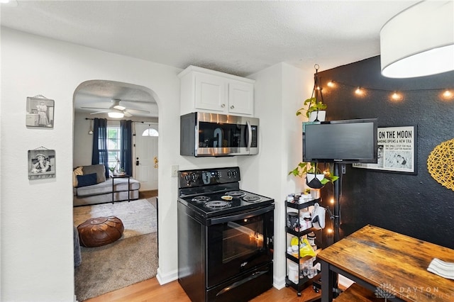 2755 S Blvd, Dayton, OH 45419 - kitchen featuring stainless steel microwave, black range with electric stovetop, arched walkways, wood finished floors, and white cabinetry