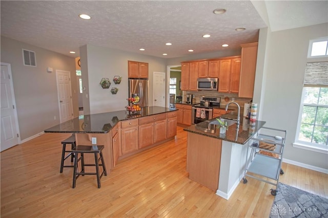 4560 James Madison Trl, Kettering, OH 45440 - kitchen featuring appliances with stainless steel finishes, a breakfast bar area, light wood-style flooring, baseboards, and recessed lighting