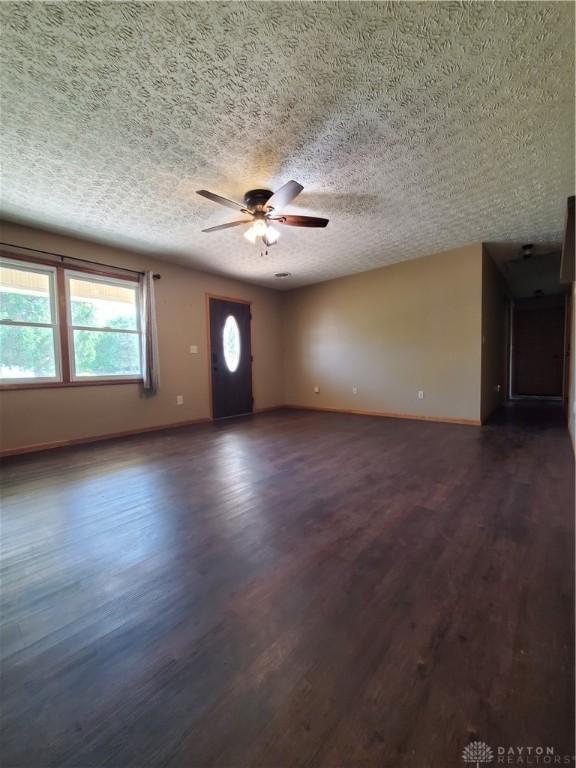 1261 Dusty Ln, West Alexandria, OH 45381 - unfurnished living room with ceiling fan, dark wood-style floors, baseboards, and a textured ceiling