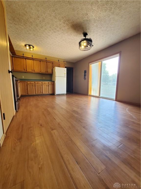1261 Dusty Ln, West Alexandria, OH 45381 - unfurnished living room with light wood finished floors and a textured ceiling