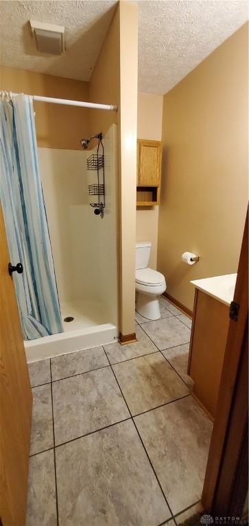 1261 Dusty Ln, West Alexandria, OH 45381 - bathroom featuring a textured ceiling, a shower stall, vanity, toilet, and tile patterned floors