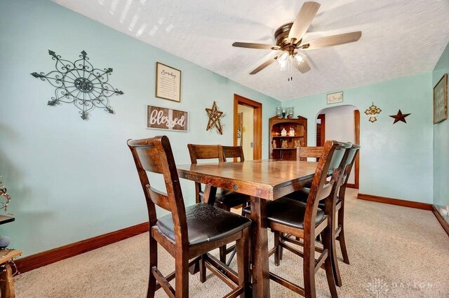 4975 Hamilton Eaton Rd, Hamilton, OH 45013 - dining area featuring arched walkways, light colored carpet, baseboards, a textured ceiling, and ceiling fan