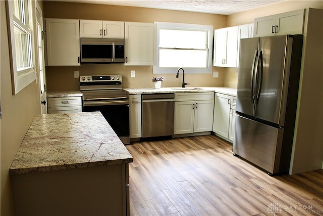 5317 Plainfield Rd, Dayton, OH 45432 - kitchen featuring appliances with stainless steel finishes, a sink, light wood-type flooring, and light stone countertops
