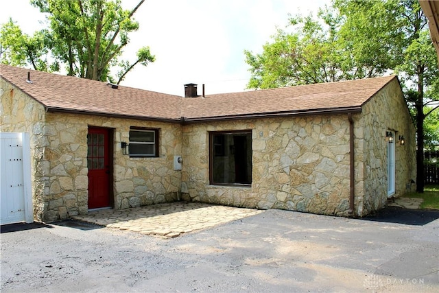 5317 Plainfield Rd, Dayton, OH 45432 - back of house featuring stone siding, roof with shingles, a chimney, and a patio
