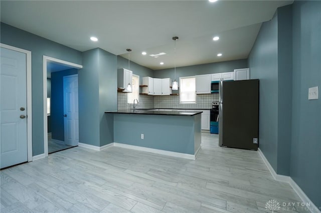 3409 E 5th St, Dayton, OH 45403 - kitchen featuring appliances with stainless steel finishes, dark countertops, a sink, backsplash, and a peninsula