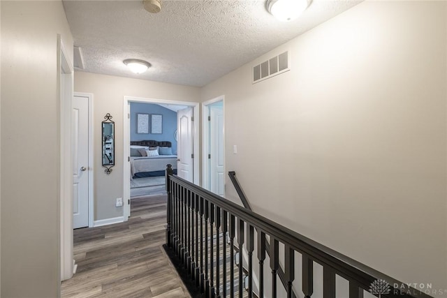 1199 Whitetail Dr, Fairborn, OH 45324 - hallway featuring light wood finished floors, an upstairs landing, a textured ceiling, and baseboards