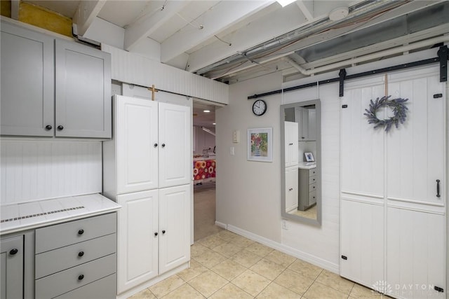 1199 Whitetail Dr, Fairborn, OH 45324 - kitchen featuring gray cabinetry, light countertops, a barn door, light tile patterned flooring, and baseboards