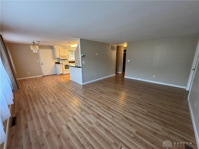 3645 Endover Rd, Dayton, OH 45439 - unfurnished living room featuring baseboards, light wood-style floors, and a chandelier