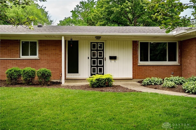 4424 Appleton Pl, Kettering, OH 45440 - doorway to property featuring brick siding, a lawn, and a shingled roof