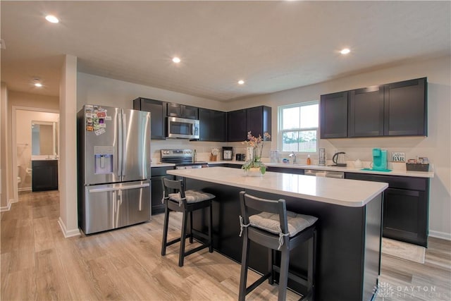 95 Whitney Way, West Milton, OH 45383 - kitchen with stainless steel appliances, light countertops, a breakfast bar area, a center island, and light wood-style floors