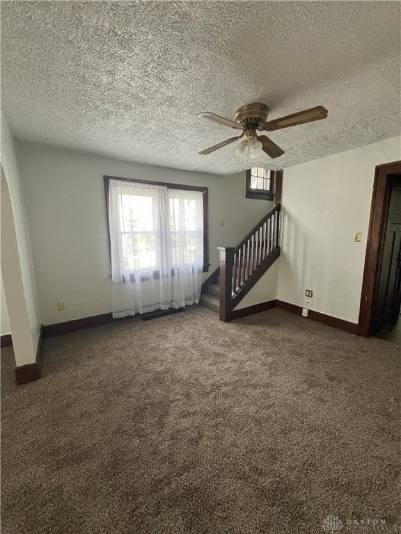 2821 E 5th St Unit 2819, Dayton, OH 45403 - unfurnished living room featuring a ceiling fan, carpet, stairs, and a textured ceiling
