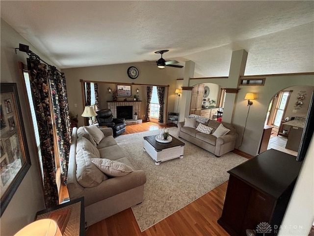 95 Fox Harbor Dr, Troy, OH 45373 - living area featuring arched walkways, ceiling fan, wood finished floors, vaulted ceiling, and a brick fireplace