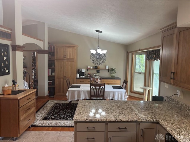 95 Fox Harbor Dr, Troy, OH 45373 - kitchen with vaulted ceiling, a chandelier, a peninsula, a textured ceiling, and decorative light fixtures