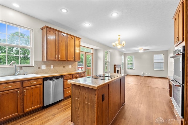 2159 Bassett Ct, Beavercreek, OH 45434 - kitchen with stainless steel appliances, a sink, a chandelier, a fireplace, and a kitchen island
