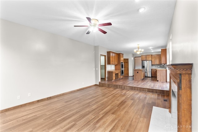 2159 Bassett Ct, Beavercreek, OH 45434 - unfurnished living room featuring a chandelier, wood finished floors, baseboards, a ceiling fan, and a sink