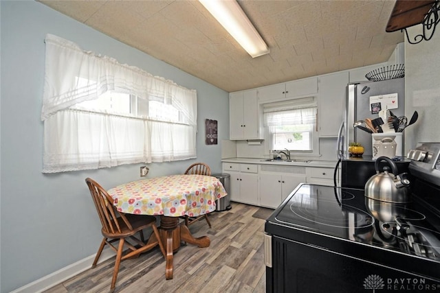 1064 Wilmington Ave, Dayton, OH 45420 - kitchen featuring black range with electric stovetop, a sink, light wood-style flooring, and freestanding refrigerator