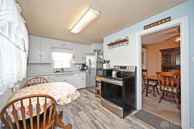 1064 Wilmington Ave, Dayton, OH 45420 - kitchen with appliances with stainless steel finishes, a sink, light wood finished floors, and white cabinets