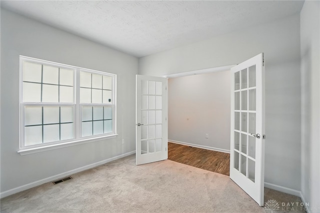 344 Warm Springs Dr, Fairborn, OH 45324 - spare room featuring french doors, carpet floors, baseboards, and a textured ceiling