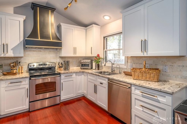 1126 Justin Ridge Way, Waynesville, OH 45068 - kitchen featuring appliances with stainless steel finishes, custom exhaust hood, a sink, lofted ceiling, and white cabinets