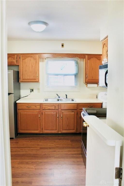 2589 Midvale St, Dayton, OH 45420 - kitchen with freestanding refrigerator, range, a sink, dark wood finished floors, and light countertops
