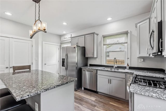 1153 Highridge Ave, Dayton, OH 45420 - kitchen with appliances with stainless steel finishes, gray cabinets, wood finished floors, dark stone counters, and a kitchen breakfast bar