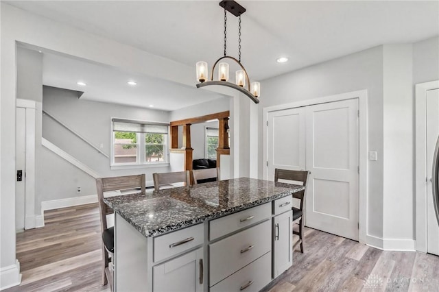 1153 Highridge Ave, Dayton, OH 45420 - kitchen with light wood finished floors, a kitchen breakfast bar, hanging light fixtures, dark stone counters, and recessed lighting
