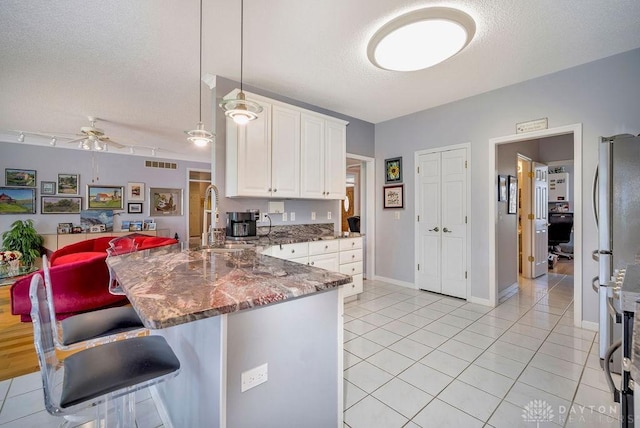 1668 Nichole Ct, Hamilton, OH 45013 - kitchen featuring a sink, a peninsula, a ceiling fan, light tile patterned floors, and a textured ceiling