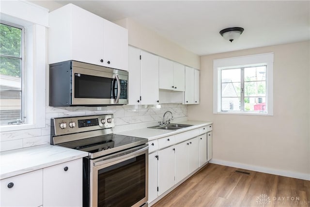 1208 Hale Ave, Dayton, OH 45419 - kitchen with appliances with stainless steel finishes, a sink, decorative backsplash, and light wood finished floors