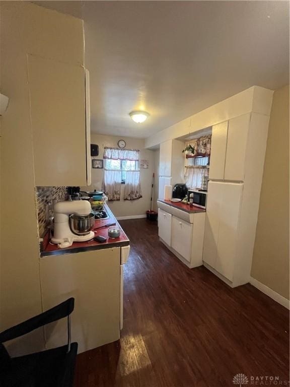 960 Sherwood Dr, Dayton, OH 45406 - kitchen with white cabinetry, dark wood-style flooring, decorative backsplash, baseboards, and stainless steel microwave