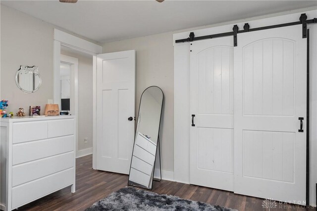 559 Stover Rd, West Alexandria, OH 45381 - unfurnished bedroom featuring a barn door, dark wood-style flooring, and baseboards