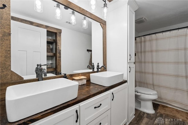 559 Stover Rd, West Alexandria, OH 45381 - bathroom featuring double vanity, toilet, wood finished floors, and curtained shower