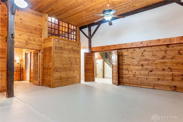 9891 Sugar St, Germantown, OH 45327 - unfurnished living room with stairs, finished concrete floors, wood walls, high vaulted ceiling, and ceiling fan