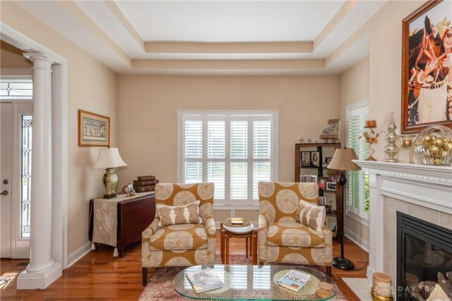 2082 Tamarack Ridge Ct, Beavercreek, OH 45431 - living area with ornate columns, a tiled fireplace, wood finished floors, and a tray ceiling