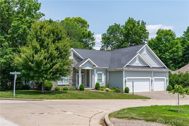 2082 Tamarack Ridge Ct, Beavercreek, OH 45431 - view of front of home featuring driveway, a front yard, an attached garage, a shingled roof, and stone siding