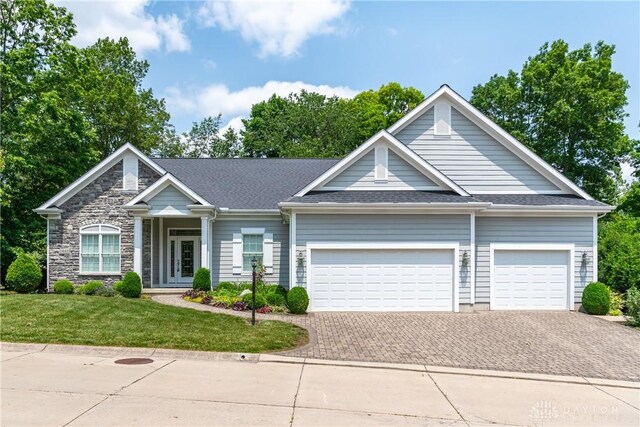 2082 Tamarack Ridge Ct, Beavercreek, OH 45431 - view of front facade featuring decorative driveway, an attached garage, a front yard, stone siding, and a shingled roof