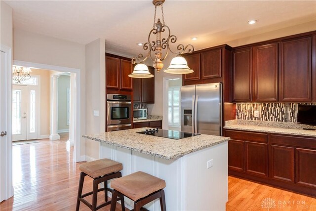 2082 Tamarack Ridge Ct, Beavercreek, OH 45431 - kitchen with appliances with stainless steel finishes, a chandelier, backsplash, a kitchen island, and light wood finished floors
