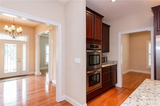 2082 Tamarack Ridge Ct, Beavercreek, OH 45431 - kitchen with appliances with stainless steel finishes, a chandelier, light wood-type flooring, light stone countertops, and decorative columns