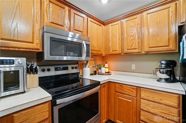 5193 Horseshoe Dr, Lewisburg, OH 45338 - kitchen with stainless steel appliances, light countertops, a textured ceiling, and brown cabinetry