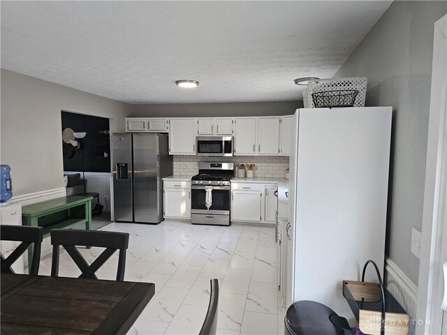 1147 Spegele Ct, Xenia, OH 45385 - kitchen with stainless steel appliances, light countertops, light marble finish floors, white cabinets, and decorative backsplash