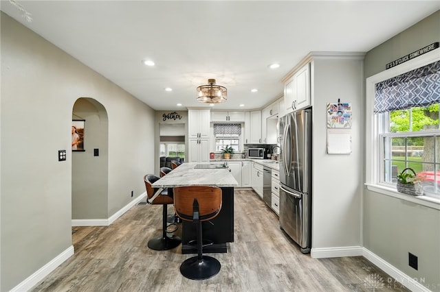 646 Barnhart Rd, Troy, OH 45373 - kitchen featuring appliances with stainless steel finishes, baseboards, light wood-style floors, a kitchen island, and arched walkways