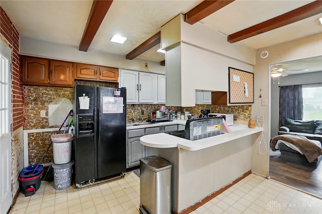 1432 Raybell Dr, Xenia, OH 45385 - kitchen with black fridge with ice dispenser, a peninsula, beam ceiling, backsplash, and light countertops