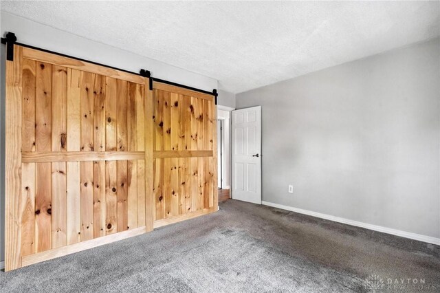 4278 Crownwood Ave, Dayton, OH 45415 - unfurnished bedroom with a barn door, carpet floors, and a textured ceiling