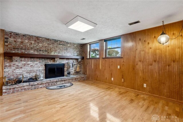 4278 Crownwood Ave, Dayton, OH 45415 - unfurnished living room with wood finished floors, a textured ceiling, a fireplace, and wood walls
